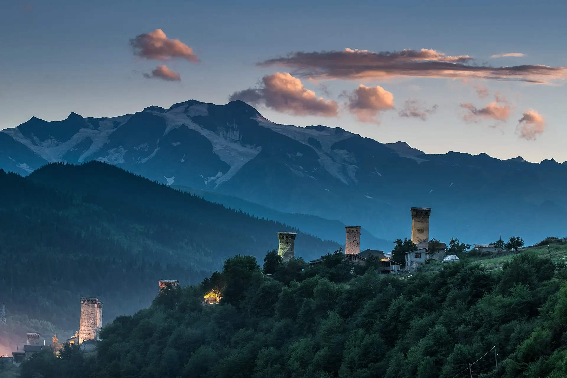 Svan towers of Mestia at dusk beneath the snow-capped Caucasus range, Upper Svaneti, Georgia