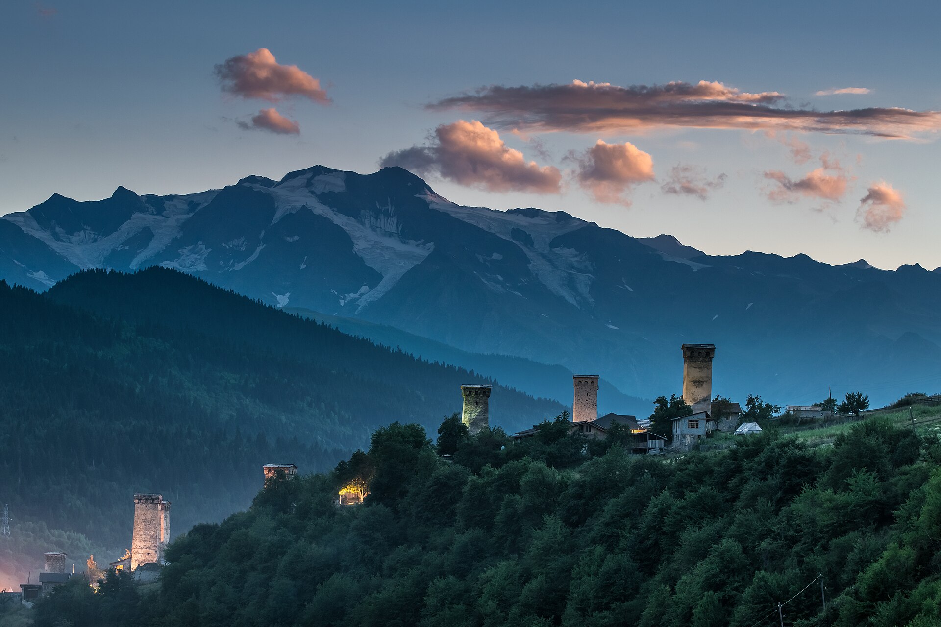 Svan towers of Mestia at dusk beneath the snow-capped Caucasus range, Upper Svaneti, Georgia